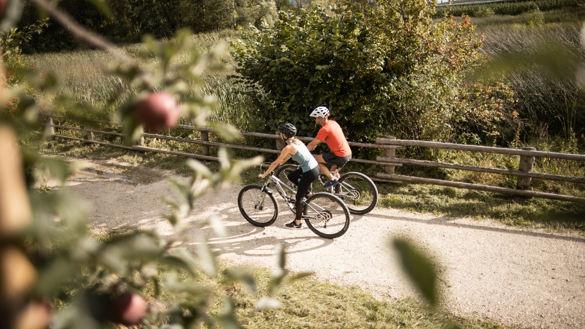 Due ciclisti pedalano su un sentiero di ghiaia in un paesaggio verde