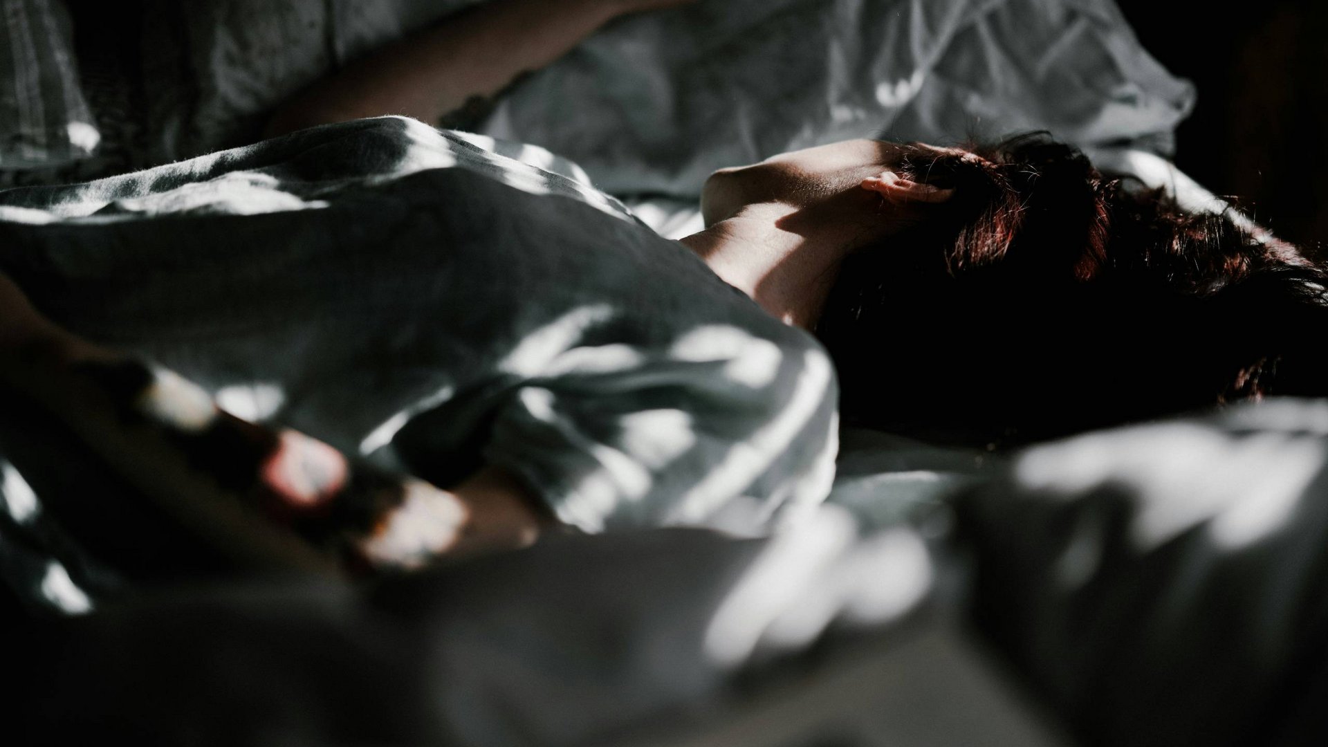 Persona che dorme nel letto con luce soffusa sul volto